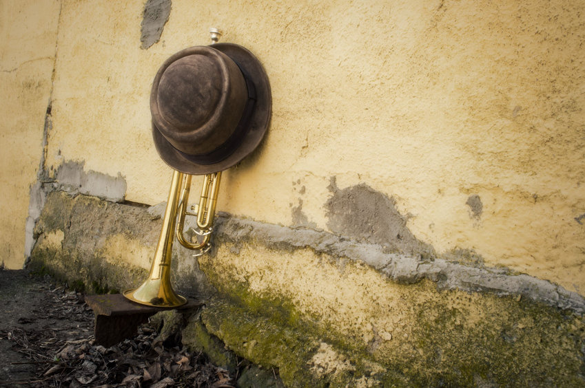 Old worn trumpet against grungy wall with pork pie style top hat