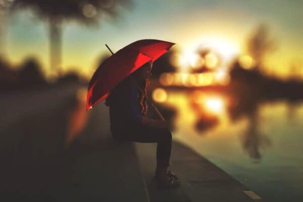 Women sat under a red umbrella