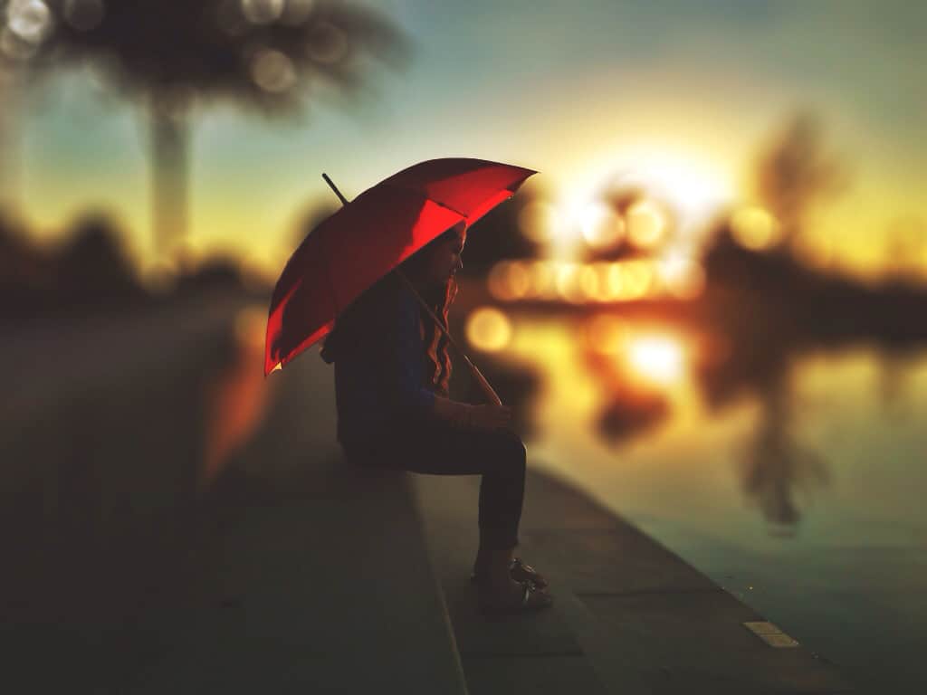 Women sat under a red umbrella