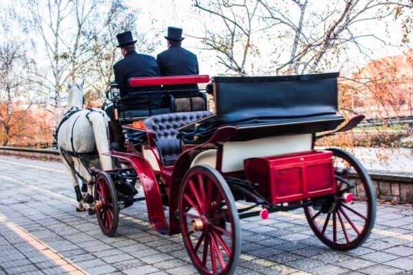 Two men wearing top hats riding a carriage