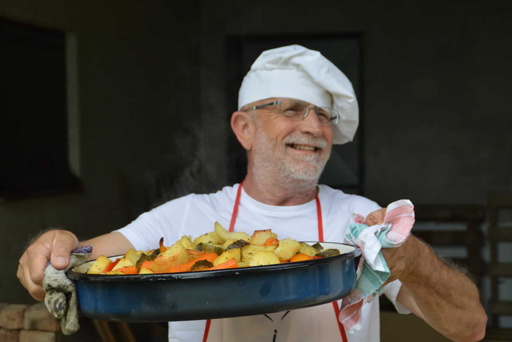 Chef wearing g a chef hat carrying food