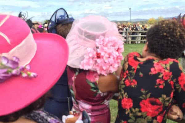 Women wearing hats at horse racing event