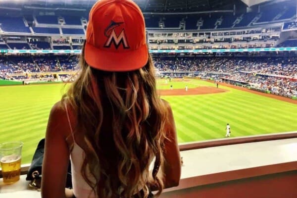 women earring baseball cap at a game with long wavy hair
