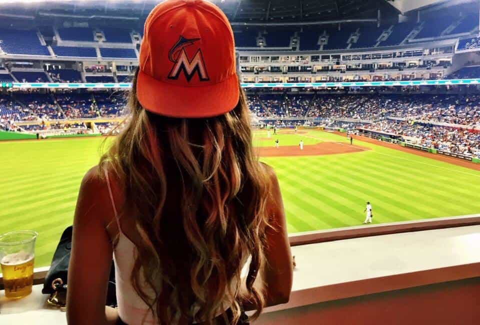 women earring baseball cap at a game with long wavy hair