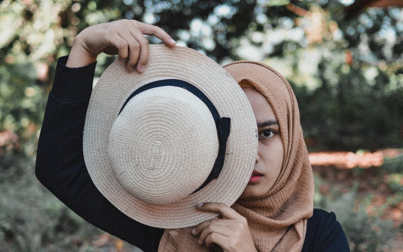 woman wearing hijab and holding a panama hat