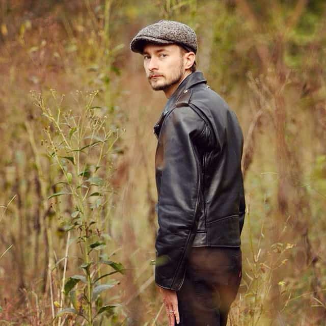 Man wearing an ascot hat with leather jacket