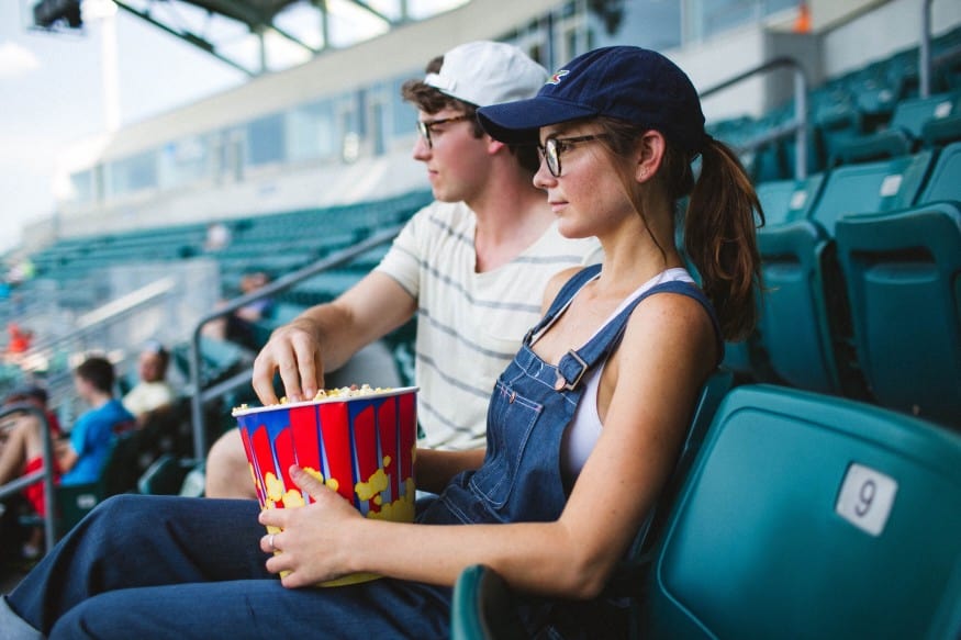 Women watching a ball game with baseball cap and pony tail