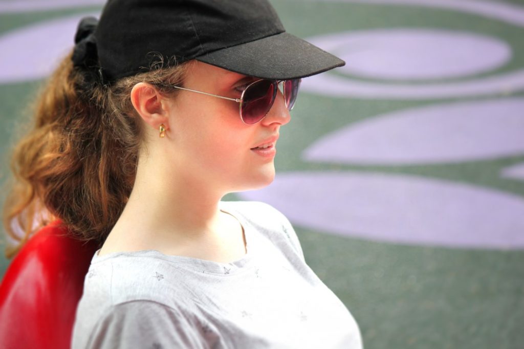 woman wearing sung glasses with baseball cap