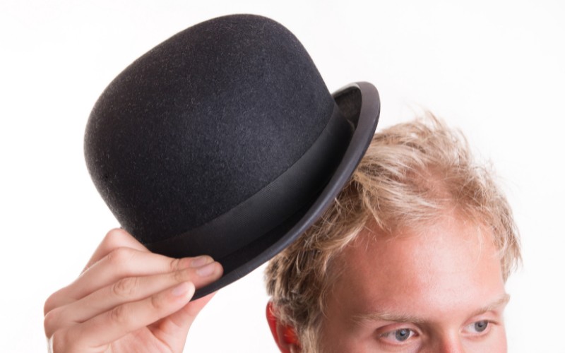 man taking off bowler hat