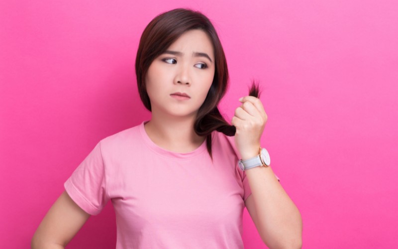 woman holding her hair looking at split ends