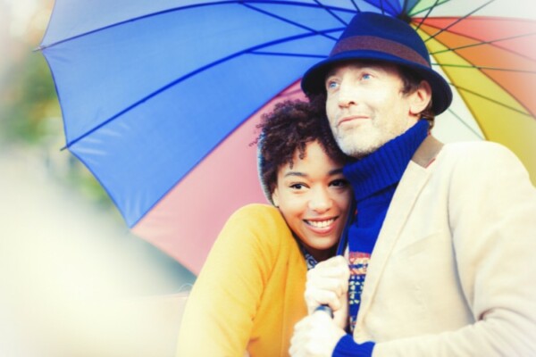 A couple wearing hats under an umbrella