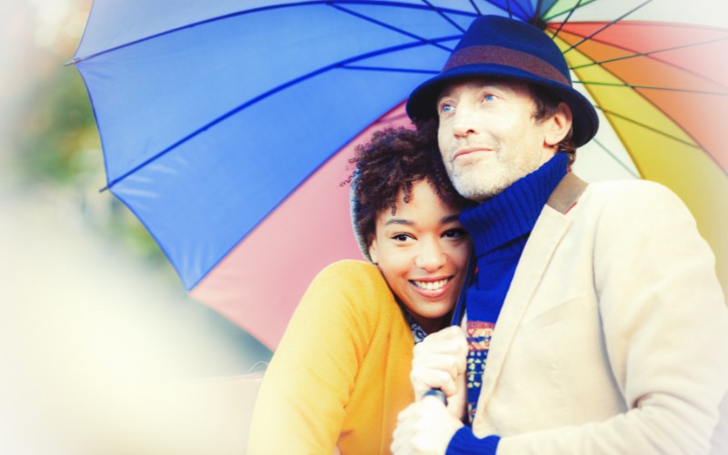 A couple wearing hats under an umbrella