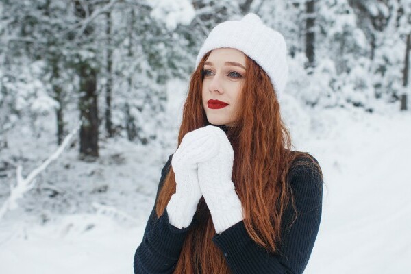 Woman wearing white gloves and hat in the snow