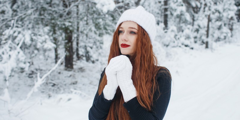 Woman wearing white gloves and hat in the snow