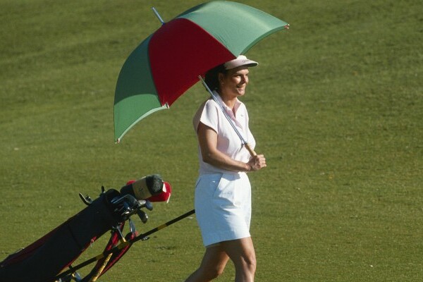 Woman playing golf carrying a golf umbrella