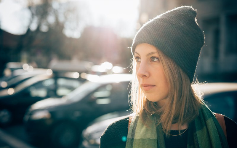 Woman wearing a beanie under the sun in the city