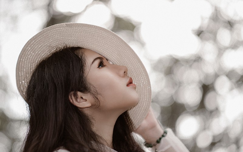 Woman with dark hair wearing a white hat