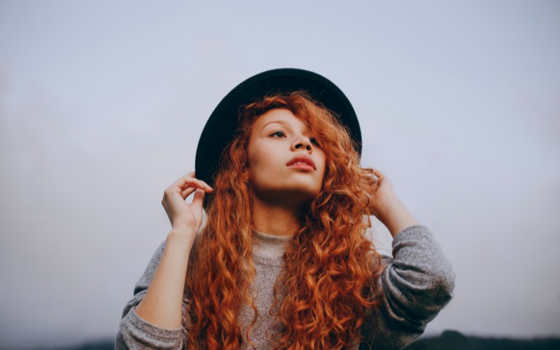 Woman with red hair wearing a black hat