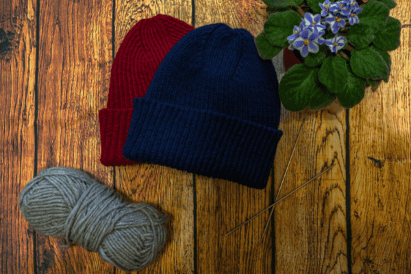 Wool hats on wooden table next to ball of wool