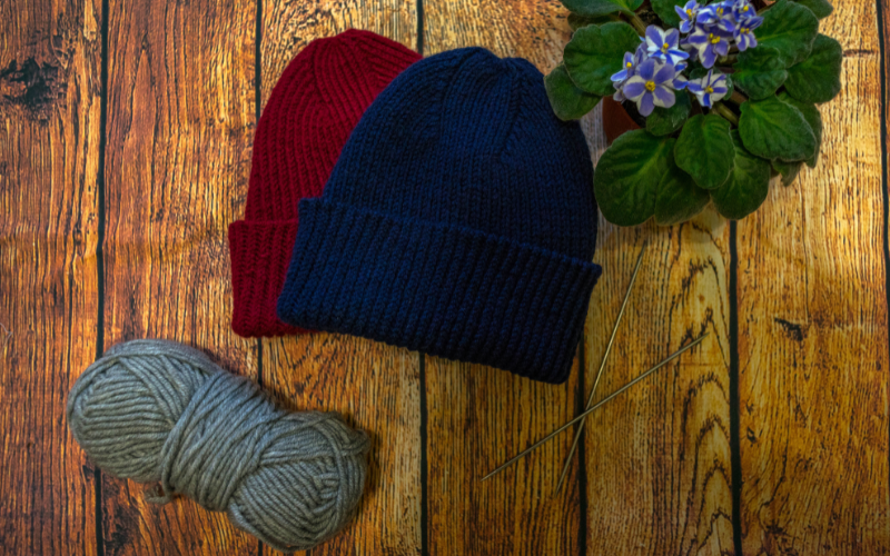 Wool hats on wooden table next to ball of wool